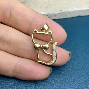 Vue détaillée du pendentif chat doré, queue en zirconium pavé et élégant nœud papillon.