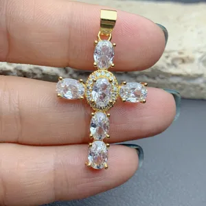 Ciondolo a croce dorato dettagliato con pietre di zirconia cubica ovali scintillanti.