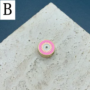 Perle ronde dorée avec motif œil turc en métal et émail rose, idéale pour création bijoux.