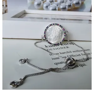 Silver adjustable mother of pearl bracelet with colorful cubic zirconia halo pendant.