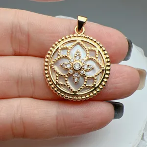 Ciondolo rotondo placcato oro con madreperla bianca e motivo floreale in zircone lucido.