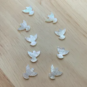 Primer plano de cuentas de nácar blanco en forma de paloma, ideales para joyería DIY.