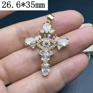 Primo piano del ciondolo a croce dorato con zirconi scintillanti e motivo occhio.
