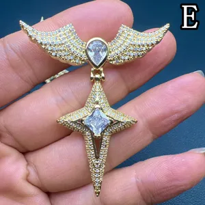 Gros plan détail du pendentif croix aile en zircon luxueux, pierres brillantes, ton or.