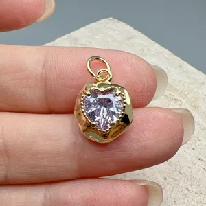 Detail shot of a minimalist gold-plated heart pendant featuring a sparkling purple cubic zirconia.