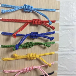 Detailed view of colorful braided rope adjustable bracelets displayed neatly on a wooden board.