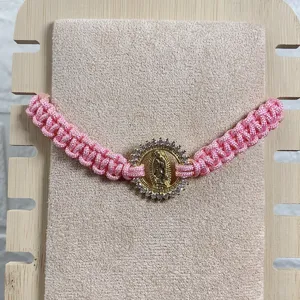 Adjustable pink woven cord bracelet featuring a gold tone Guadalupe pendant with clear zirconia.