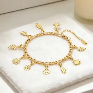 Nahaufnahme des goldenen Edelstahl-Charm-Armbands mit verschiedenen Blumen- und Blattanhängern.