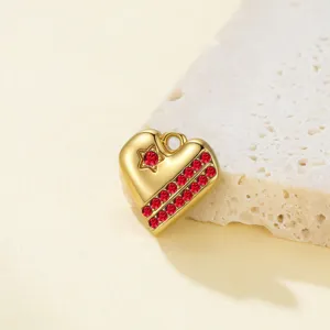 Primer plano detallado de un colgante de corazón dorado con circonitas rojas y estrella.