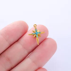 Close-up of gold stainless steel star pendant with sparkling blue rhinestones on finger.