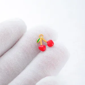 Charming gold-tone cherry pendant with red and green enamel, perfect for DIY jewelry making.