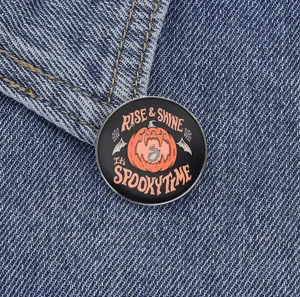 Close-up detail of the Halloween pumpkin metal brooch pin featuring dark spooky slogan text.