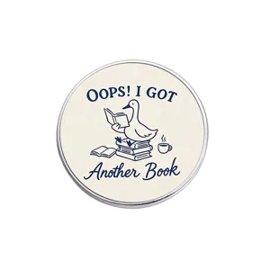 Cute reading duck metal brooch detail, artistic cartoon badge design, clothing accessory.