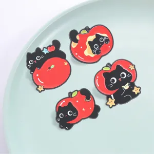 Close-up detail of cute black cat and red apple enamel pins, lovely cartoon brooch badge style.