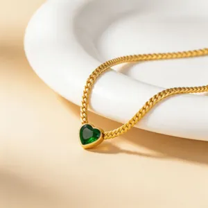 Close-up detail of gold titanium steel necklace with a green heart zircon pendant.
