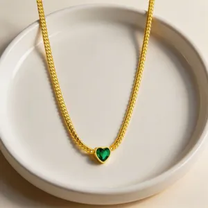 Elegant gold snake chain necklace featuring a stunning green heart crystal pendant detail.