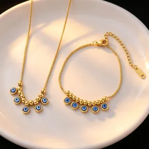 Detailed close-up of a delicate gold-toned stainless steel evil eye necklace and bracelet set.