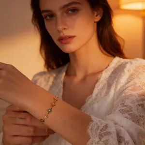 Close-up detail shot of a delicate gold chain bracelet featuring colorful enamel daisies.