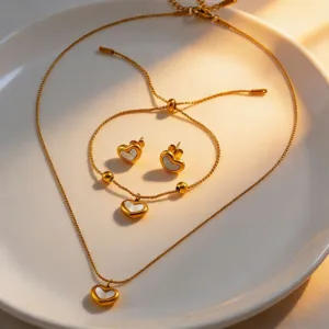 Exquisite white shell heart jewelry detail, gold titanium steel necklace bracelet set on plate.