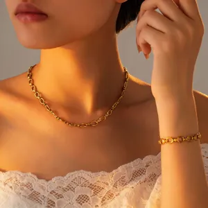 Detailed shot of gold-plated interlocking chain necklace and bracelet jewelry set for women.