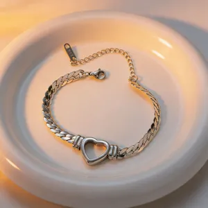 Detail van de elegante holle hart Cubaanse ketting armband op een witte keramische schaal.