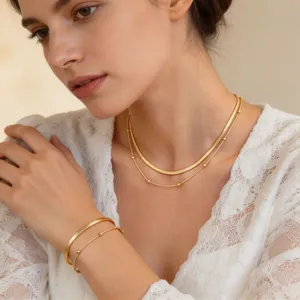 Primer plano detallado de un elegante collar de doble capa de acero de titanio dorado con cuentas.