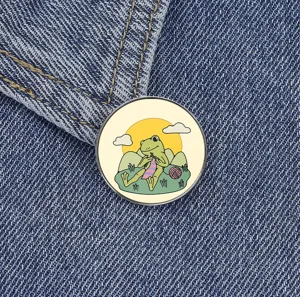 Vue rapprochée de la jolie broche en métal grenouille de dessin animés sur tissu en denim, badge.