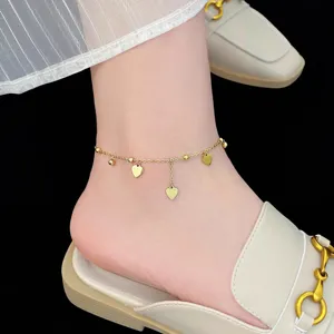 Close-up detail shot of dainty gold heart anklet with cute dangling charms and beads.