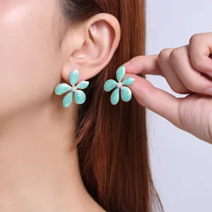 Close-up detail shot of mint green enamel flower earrings featuring a pearl center and metal trim.