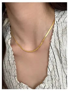 Close-up detail shot of a sleek 18k gold plated titanium steel herringbone snake chain necklace.