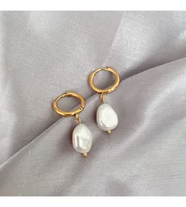 Detail shot of elegant gold hoop earrings featuring irregular baroque pearl pendants on silk.