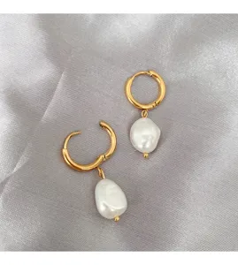 Elegant detail shot of minimalist gold hoop earrings featuring irregular baroque pearl pendants.