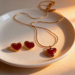Red heart necklace and earrings detail shot, elegant gold titanium steel jewelry set.
