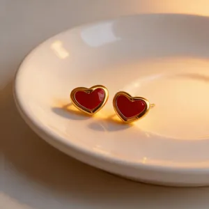 Charming red heart stud earrings with gold rim, elegant fashion jewelry detail view.