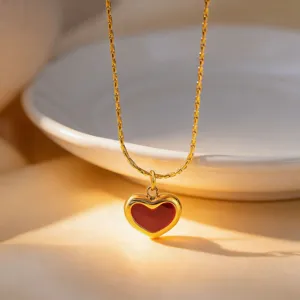 Close-up detail of the elegant gold titanium steel necklace featuring a striking red heart pendant.