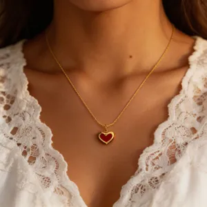 Gold tone red heart pendant necklace detail shot, delicate titanium steel jewelry for women.