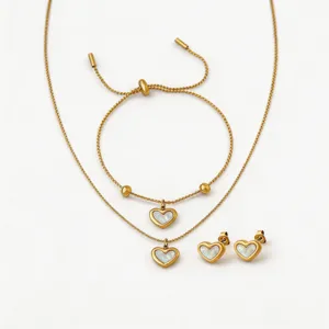Closeup details of gold titanium steel jewelry set with white mother of pearl heart pendants.