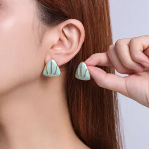 Close-up detail of the minimalist triangular enamel titanium steel earrings worn elegantly by model.