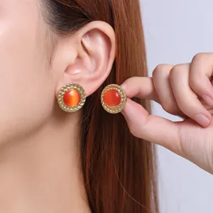 Detailed close-up view of gold stainless steel earrings with sparkling orange cat eye stones.