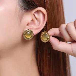 Close-up detail of vintage round stainless steel 18k gold plated cat eye stone earrings.