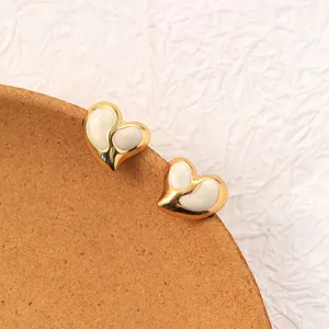 Detailed shot of gold-plated titanium steel heart earrings with white enamel finish. Close up.