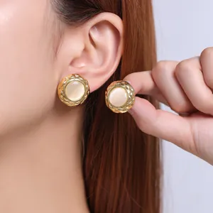 Close-up detail of vintage style gold cat-eye earrings with quilted texture bezel design.
