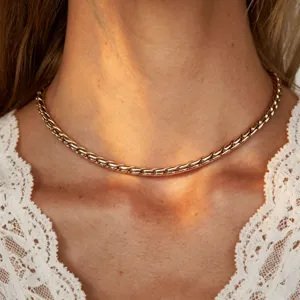 Close-up detail of a minimalist gold twisted rope chain necklace worn on neck with white lace top.
