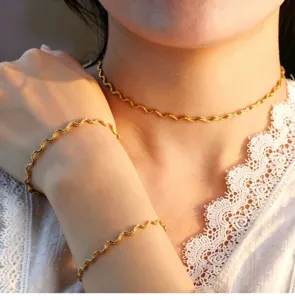 Detail view of wavy line stainless steel necklace and bracelet set in 18k gold plated finish.