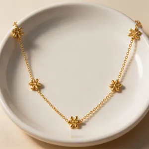 Delicate gold-plated daisy flower chain necklace stunning detail shot in white ceramic dish.