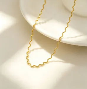 Close-up detail of a minimalist 18k gold plated wavy stainless steel chain necklace.