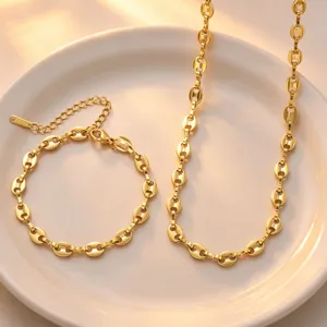 Close-up detail of gold coffee bean chain necklace and bracelet set, polished texture.
