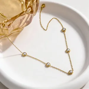 Elegant gold stainless steel station necklace with bezel-set pearls, minimalist style.