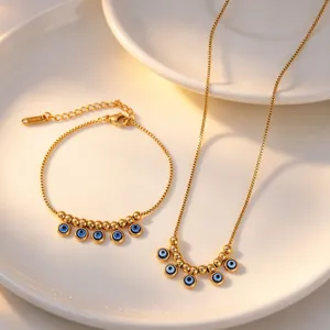 Detailed shot of evil eye charm pendant necklace and bracelet jewelry set on a white plate.