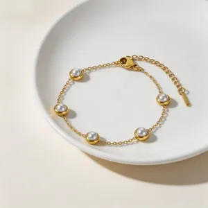Minimalist gold-tone station bracelet with elegant faux pearls, delicate chain and clasp detail.